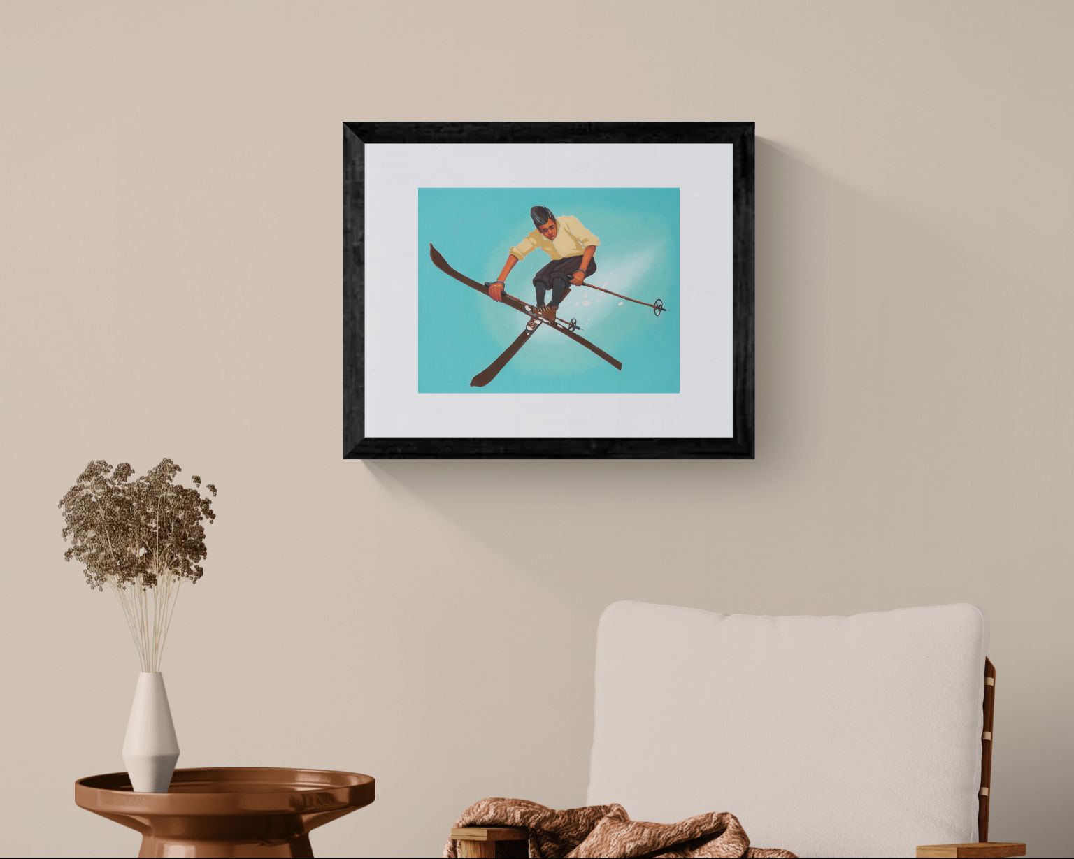 Framed artwork of a person on skis hanging on a wall above a chair and table.
