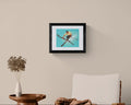 Framed artwork of a skier on a beige wall above a wooden table and chair.