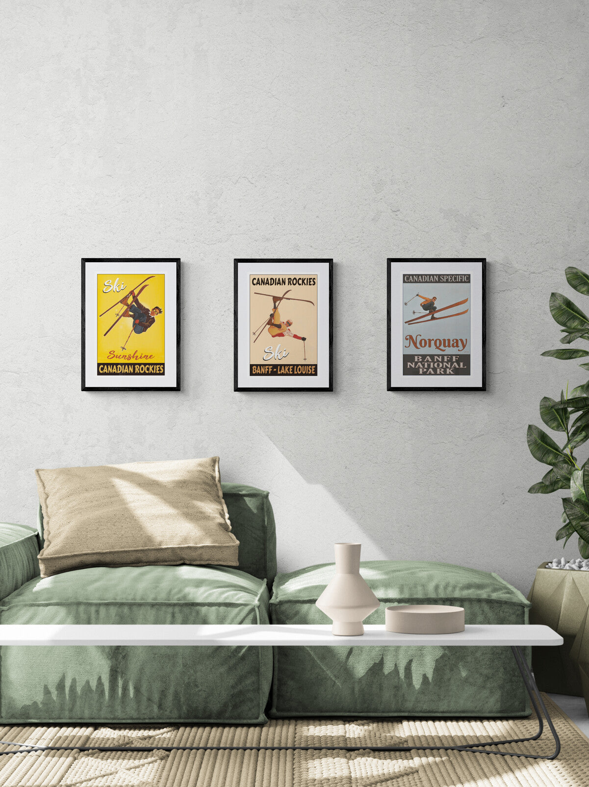 Green sofa with decorative pillows in a living room setting, featuring framed posters on the wall.