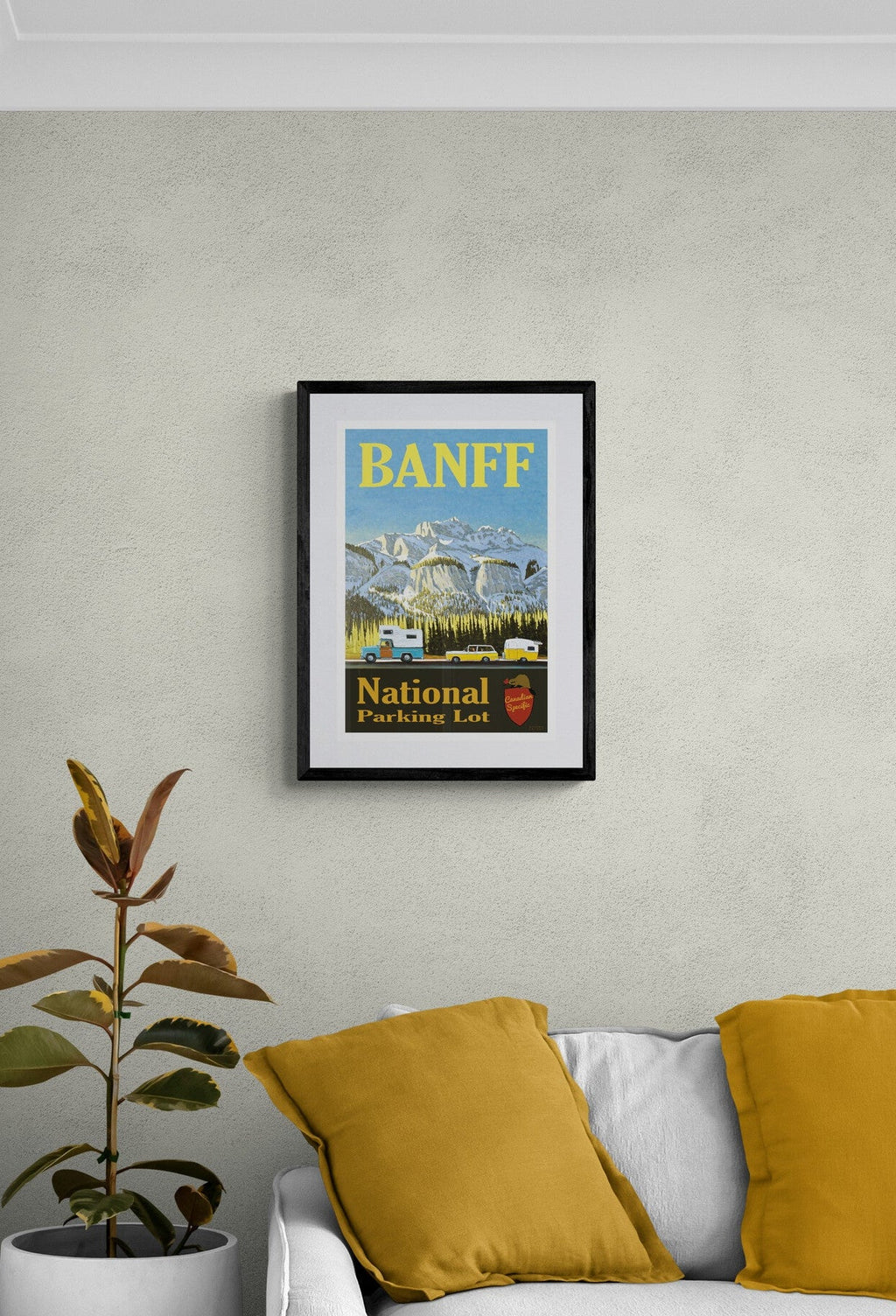 Framed Banff National Park poster on a wall above a sofa with yellow cushions.